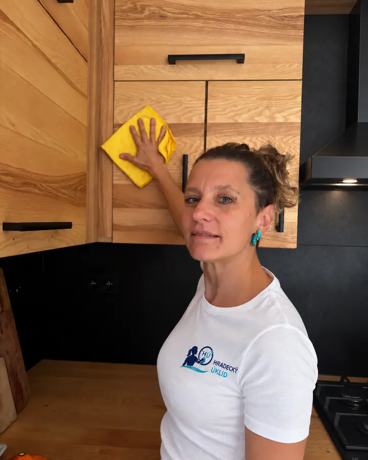 Marie Coufalová utírá kuchyňskou skříňku u digestoře